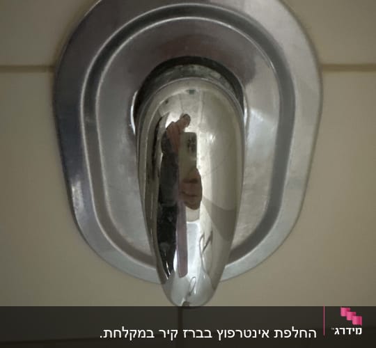 ידית ברז מתכתית על קיר אריחים